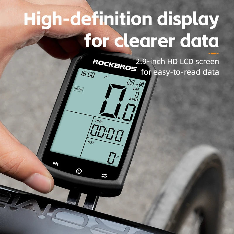 Digital cycling computer with high-definition display held by a hand, on a blurred background.
