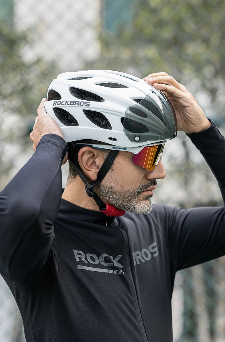 Person wearing a white helmet with 'RockBros' branding, adjusting it against a blurred outdoor background.